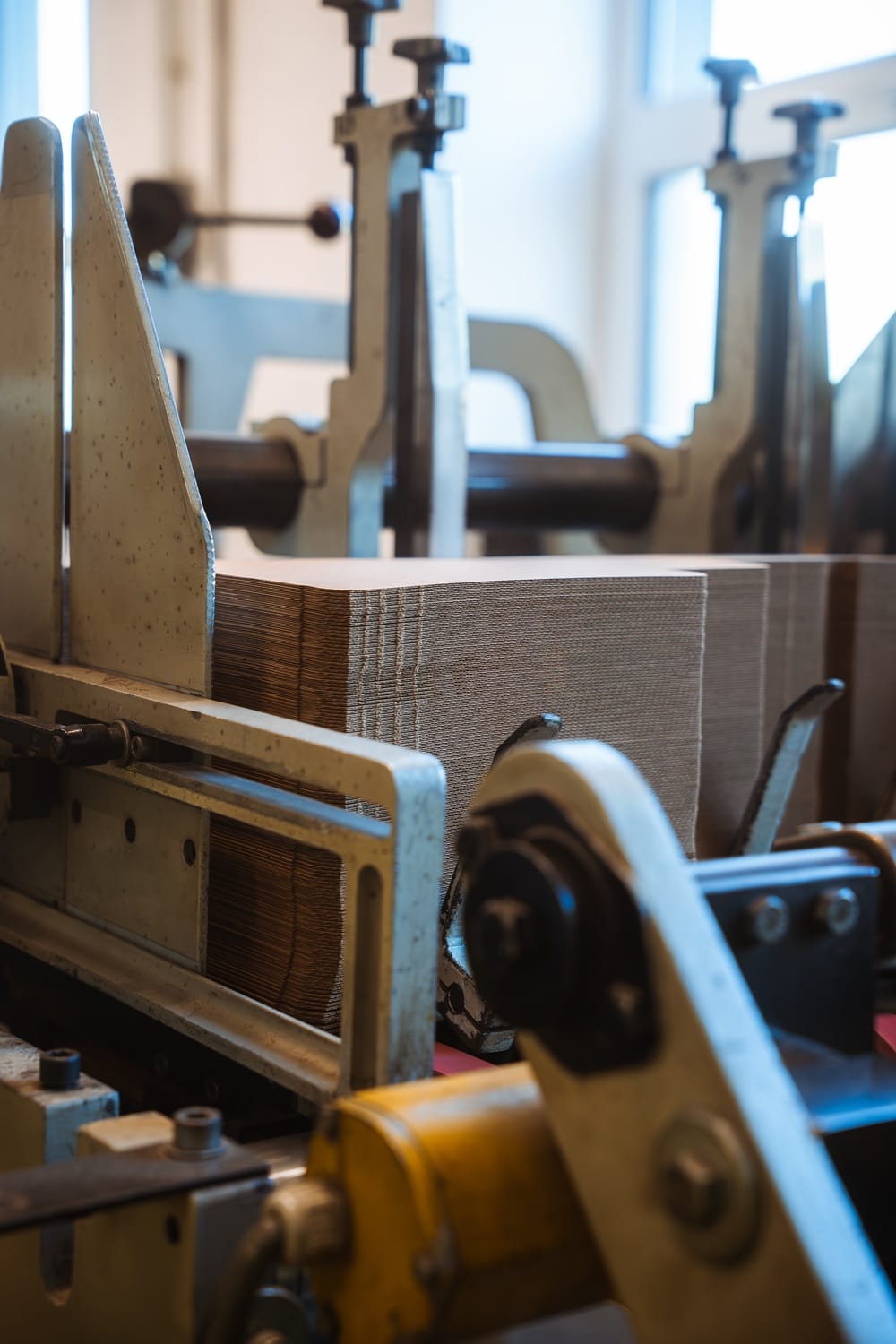 Krabice a obaly na míru: jak významně snížit logistické náklady? 29 Stoh kartonových přířezů upnutý v části výrobního stroje připravený k dalšímu zpracování nebo balení.