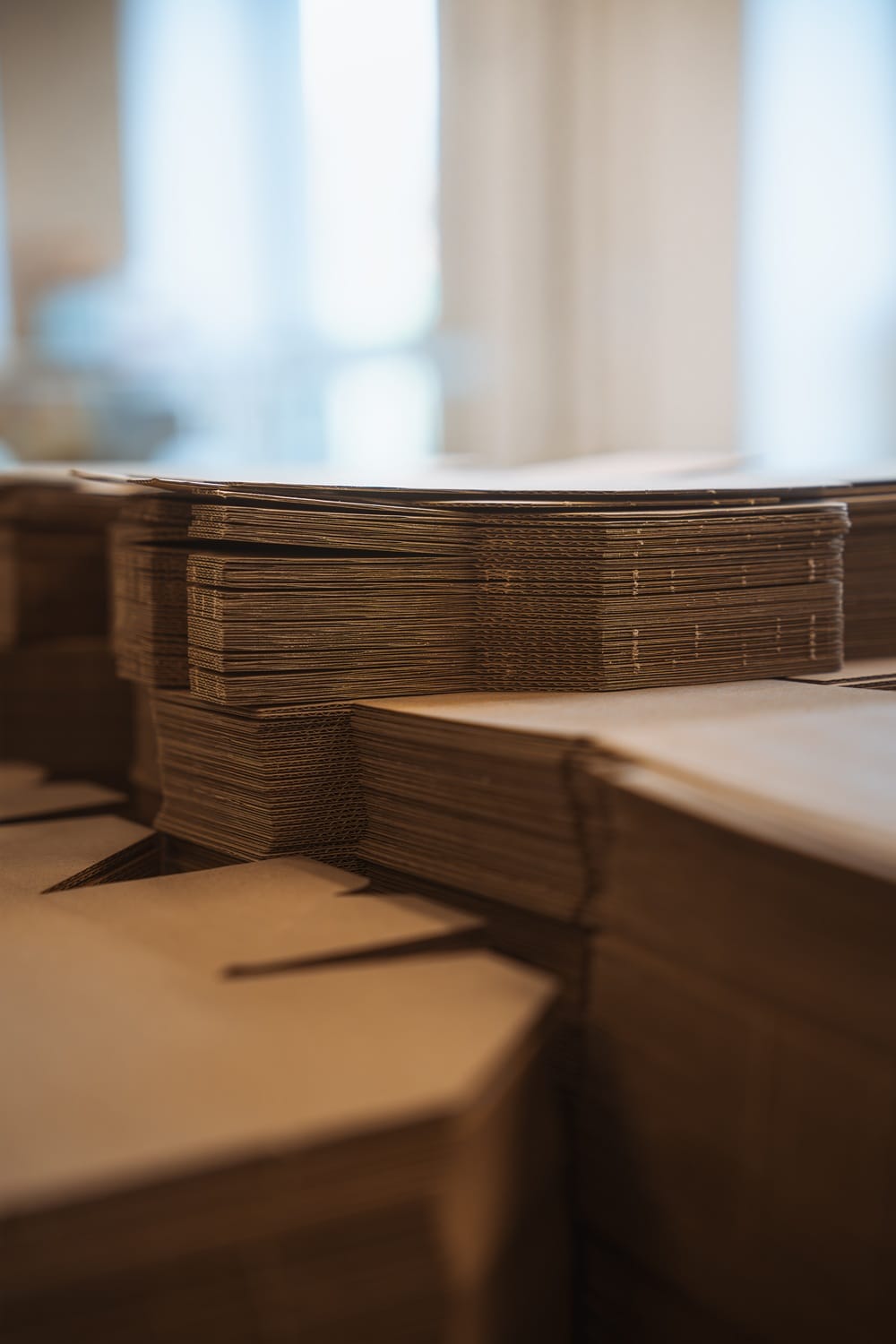 Krabice a obaly na míru: jak významně snížit logistické náklady? 10 Detail několika stohů přesně vyřezaných kartonových přířezů připravených k dalšímu zpracování.