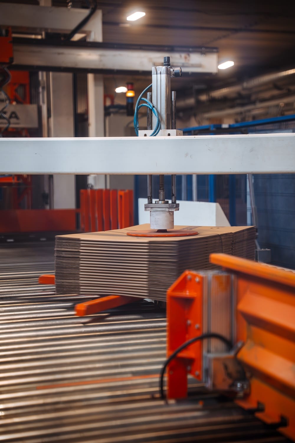 Krabice a obaly na míru: jak významně snížit logistické náklady? 30 Automatické manipulační zařízení s vakuovou hlavicí zvedá stoh kartonových přířezů na válečkové dopravníkové lince.